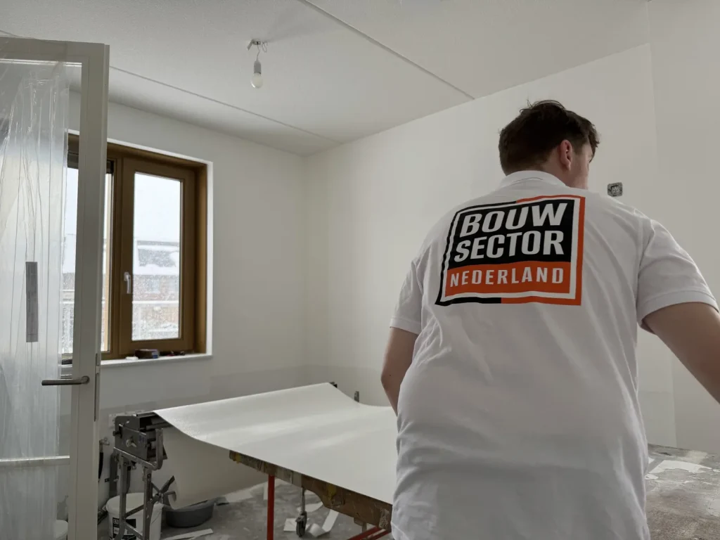 Behanger van Bouwsector Nederland trekt een baan renovlies over de plaktafel in een nieuwe slaapkamer